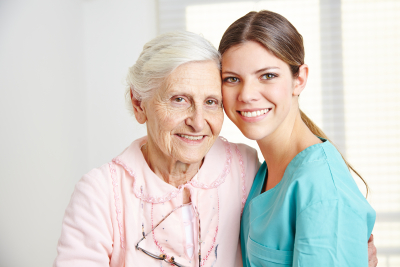 smiling caregiver embracing happy senior woman