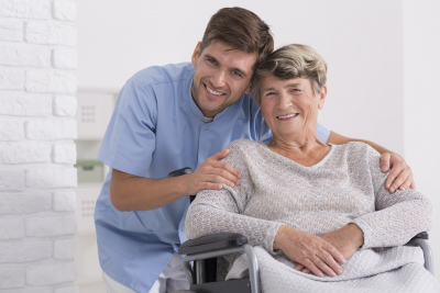 nurse hugging his senior woman patient sitting on a wheelchair